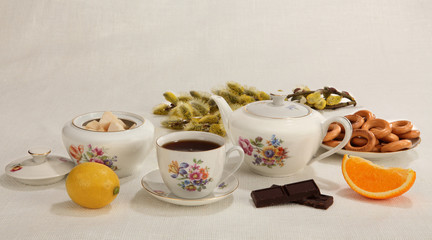 Fototapeta na wymiar Cup of tea, teapot, sugar bowl, lemon, orange slice, chocolate,