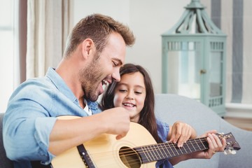 Fototapeta premium Father playing guitar with daughter