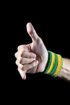 Athlete hand with yellow and green Brazil colors wristband giving a classic shaka surfer sign