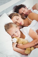 High angle view of parents sleeping with daughter 
