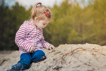 a little girl sitting and playing in the sand