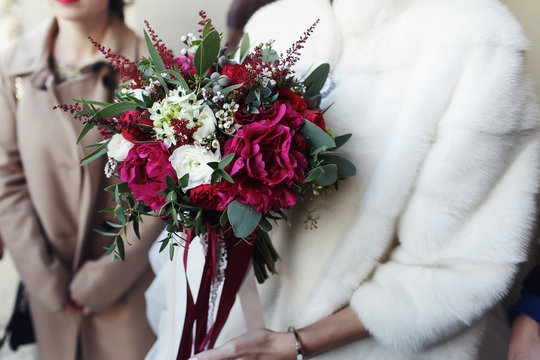 Bride In The Fur Coat Holds Red Wedding Bouquet