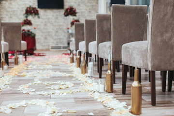 Aisle in the hall between brown chairs with white petals on the
