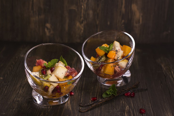 Fruit salad in glass bowls over dark background