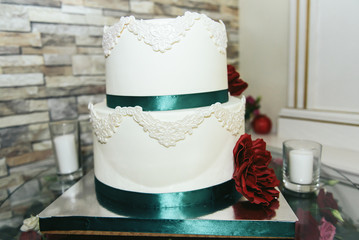 Wedding cake with green ribbon and red flower