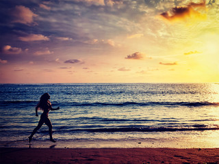 Beautiful athletic woman running along sea on the beach