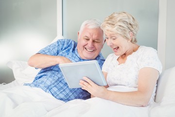 Excited senior couple using digital tablet at home