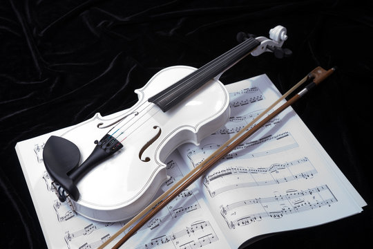 White violin isolated on black background with notes