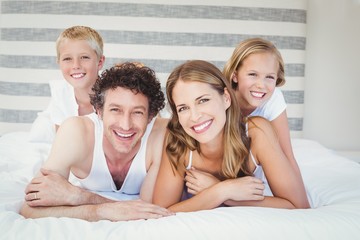 Portrait of happy family resting on bed
