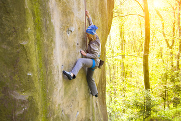 The girl climbs on the rock.