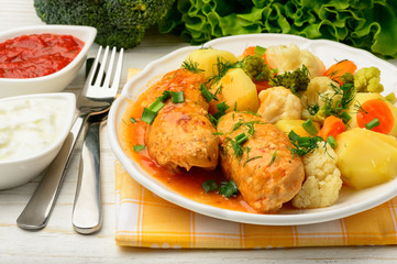 Meat stuffed rolls with vegetables and tomato sauce.
