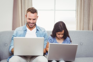 Father and daughter using laptop at home