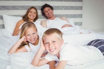 Obraz na płótnie Canvas Portrait of happy family resting on bed