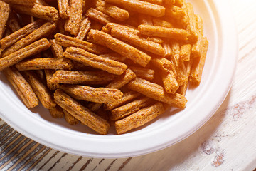 Pile of crackers on plate. White plate with bread crackers. Crispy sticks on white table. Simple snack recipe.