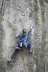 Obraz premium Athlete climbs on rock with rope.
