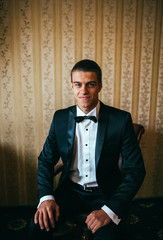 Groom in the morning on the wedding day buttoning cuffs his hands on his suit