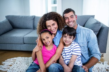 Portrait of happy family sitting together on floor