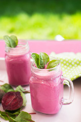 Glass of fresh beetroot juice with bets and leafs . Beetroot smoothie in jar. Pink detox. Close up. 