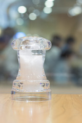 Salt and pepper inside clear container on wooden table with blur