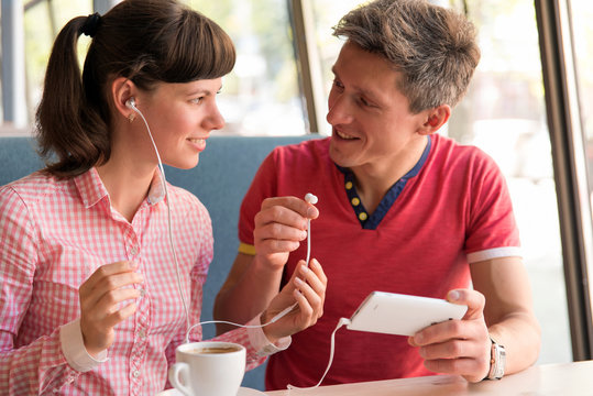 young couple listening to music in the cafe
