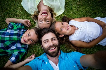 Cheerful family lying on grass in yard 