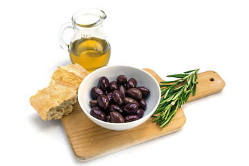 Kalamata black olives, olive oil, bread and rosemary garnish, board and white background