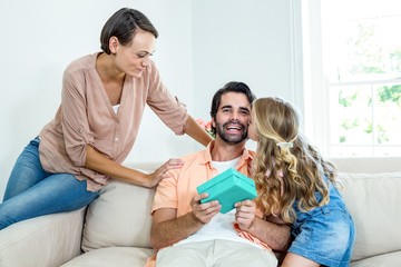 Daughter kissing father while mother sitting beside them