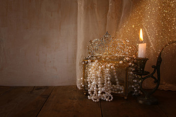 diamond queen crown, white pearls next to burning candle © tomertu