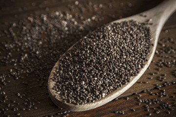 Chia seeds in kitchen spoon on wooden table, close-up