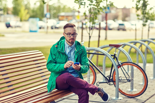 happy young hipster man with smartphone and bike