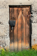 Old closed dingy wooden door in stone wall