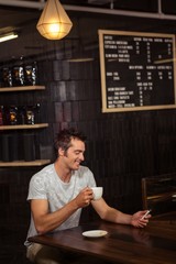 Man using his smartphone and drinking coffee