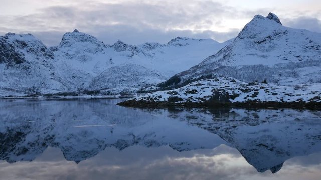 Snow covered mountains at a lake during sunset in the Lofoten islands region in Norway during winter
