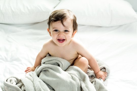 Happy shirtless baby boy playing with towel