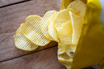 Opened pack with potato chips over wooden table