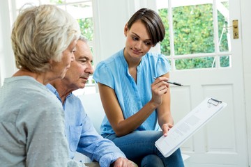 Obraz premium Senior couple reading report with female consultant