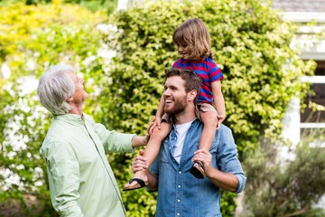 Granddad looking at son carrying grandson 