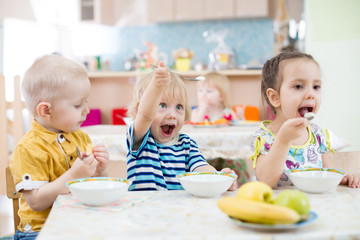 Funny little kid playing and eating in kindergarten - obrazy, fototapety, plakaty