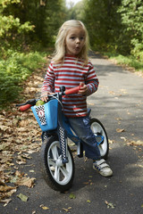 Cute little blond girl riding runbike a bicycle path, active kids sport