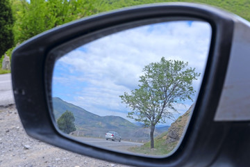reflection of the mountain road in a car rear-view mirror