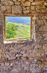 Look through window from abandoned stone house in the mountain