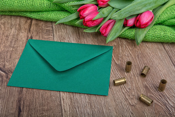 Envelope, tulips and bullets on a wooden background