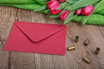 Envelope, tulips and bullets on a wooden background