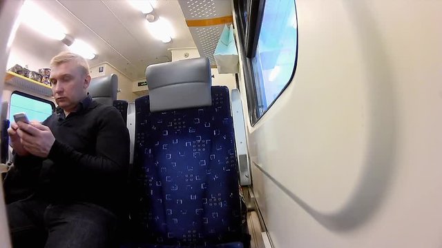 Man uses a smartphone in a compartment of a passenger train