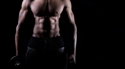  Male fitness model showing muscles in studio with a black background