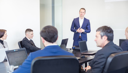 Successful team leader and business owner  leading informal in-house business meeting. Businessman working on laptop in foreground. Business and entrepreneurship concept.