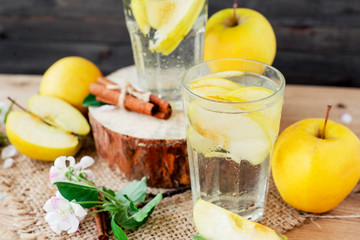 
detox , healthy and refreshing drink ,Nutritious cold sparkling water with fresh apple and cinnamon on a wooden background