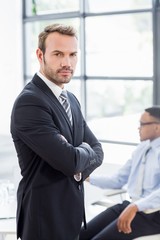 Happy businessman standing with arms crossed