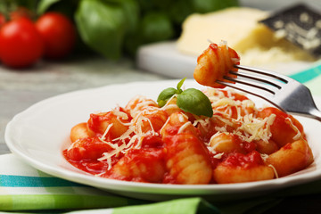 Serving gnocchi in tomato sauce with cheese. - obrazy, fototapety, plakaty