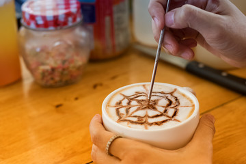 Barista creates latte art in a cup of coffee latte